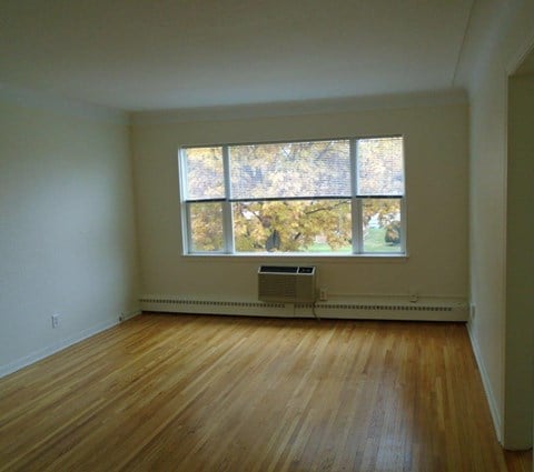 an empty living room with a large window and wooden floors